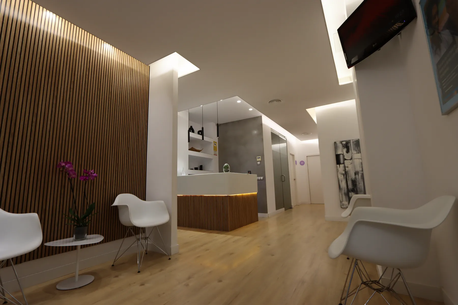 Sala de espera de Valencia Dental, con butacas blancas y pared de listones de madera